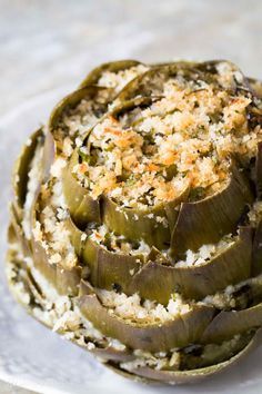 an artichoke on a plate topped with rice and seasoning