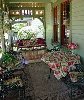 the porch is covered with floral tablecloths and chairs