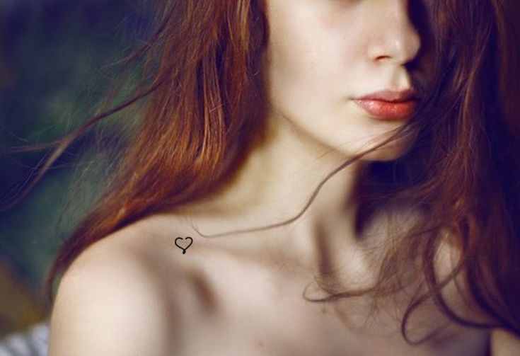 a woman with long red hair wearing a white dress and holding her hand on her shoulder