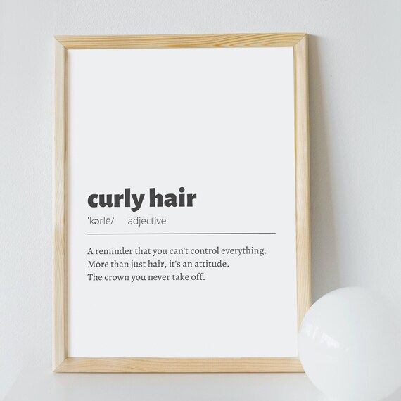 a framed poster with the words curly hair on it next to a white light bulb