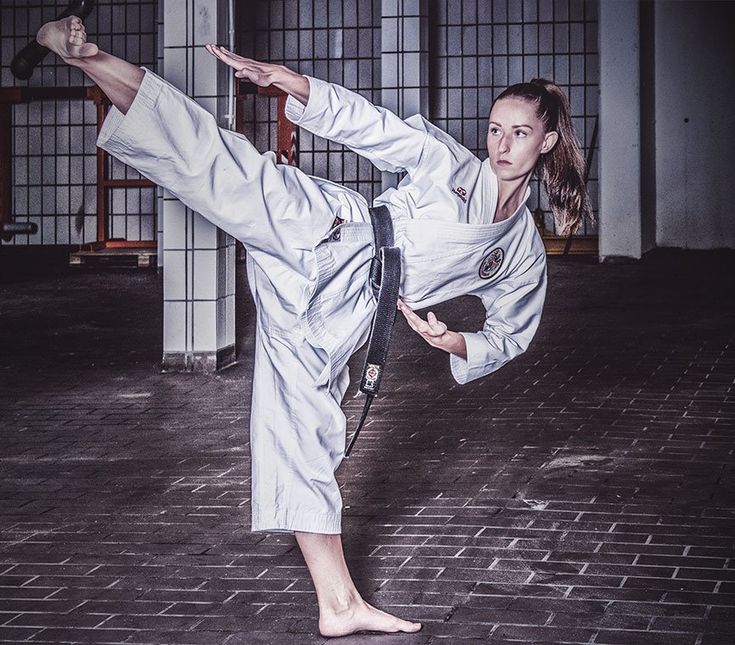 a woman doing karate moves in an indoor gym area with brick flooring and windows