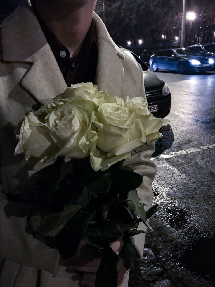 a man holding a bouquet of flowers in his hand on the side of the road