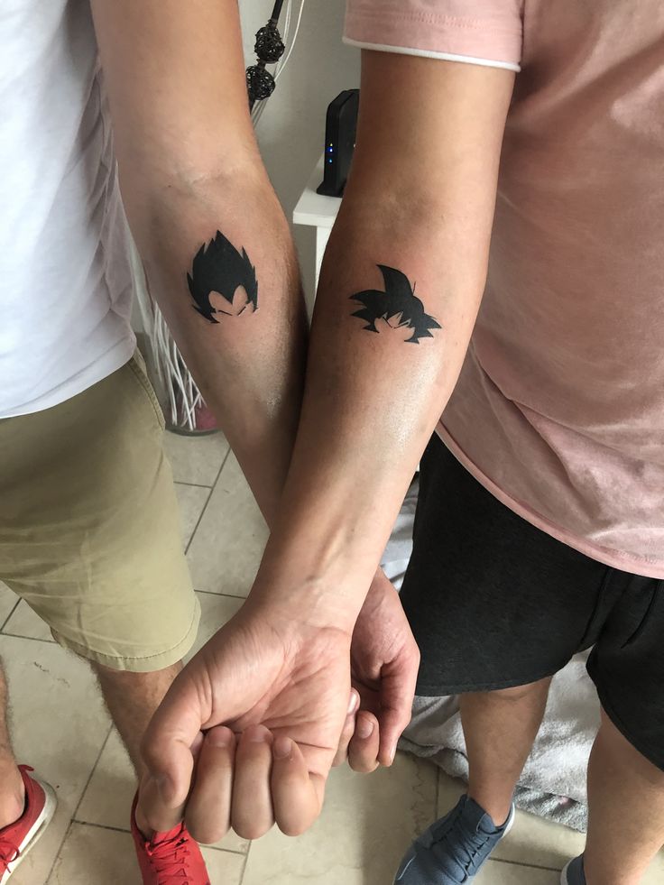 two people holding hands with tattoos on them