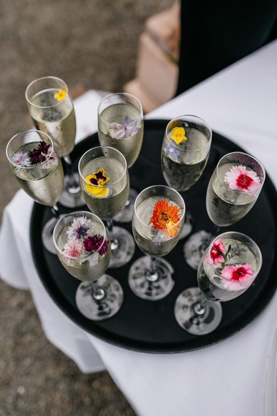 there are many wine glasses with flowers in them on the tray and one is empty