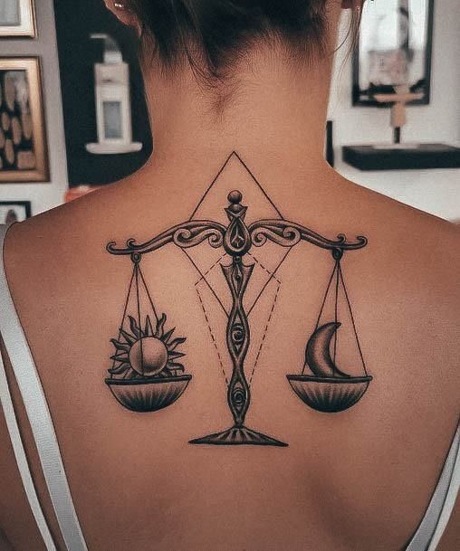 a woman's back with a libra tattoo on her left shoulder and an hour scale in the middle