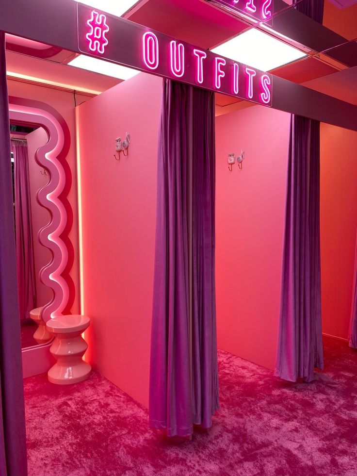 a pink room with purple curtains and a neon sign that says outfits on it