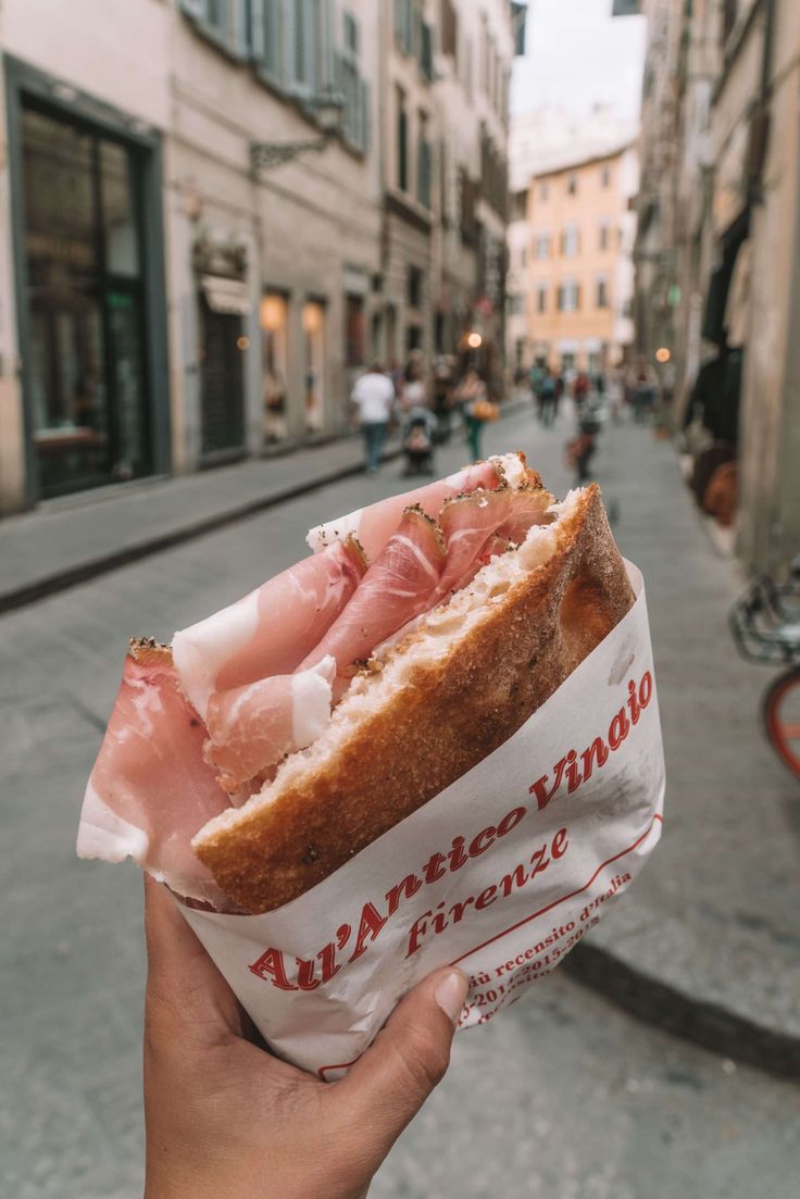 someone is holding up a sandwich in the street