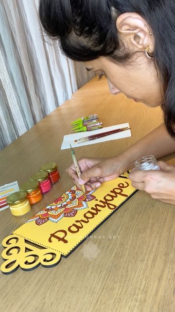 a woman sitting at a table with some crafting supplies in front of her and writing on the paper