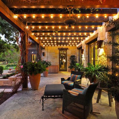 an outdoor patio covered in lights and potted plants