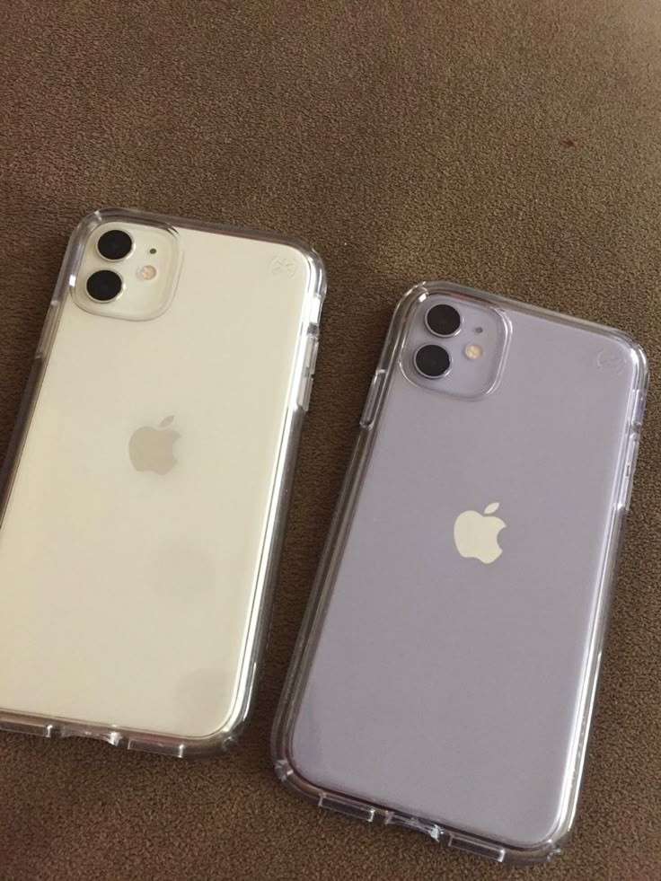 two iphones sitting next to each other on a carpeted floor in front of an apple logo