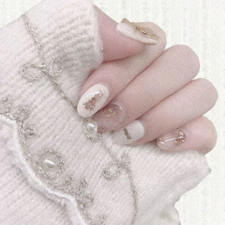 a woman's hand with white and gold manicures on her nails, holding a chain