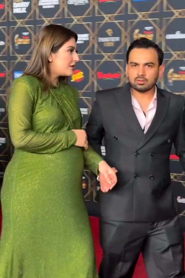 two people standing next to each other on a red carpet