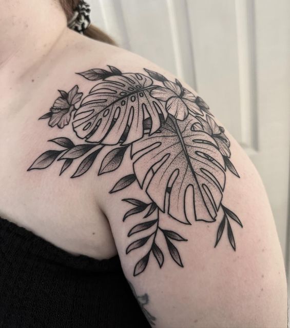 a black and white photo of a woman's shoulder with a tattoo design on it