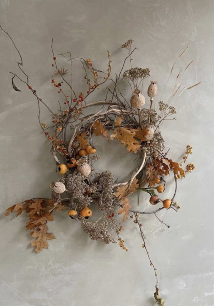 an arrangement of dried flowers and leaves on a wall