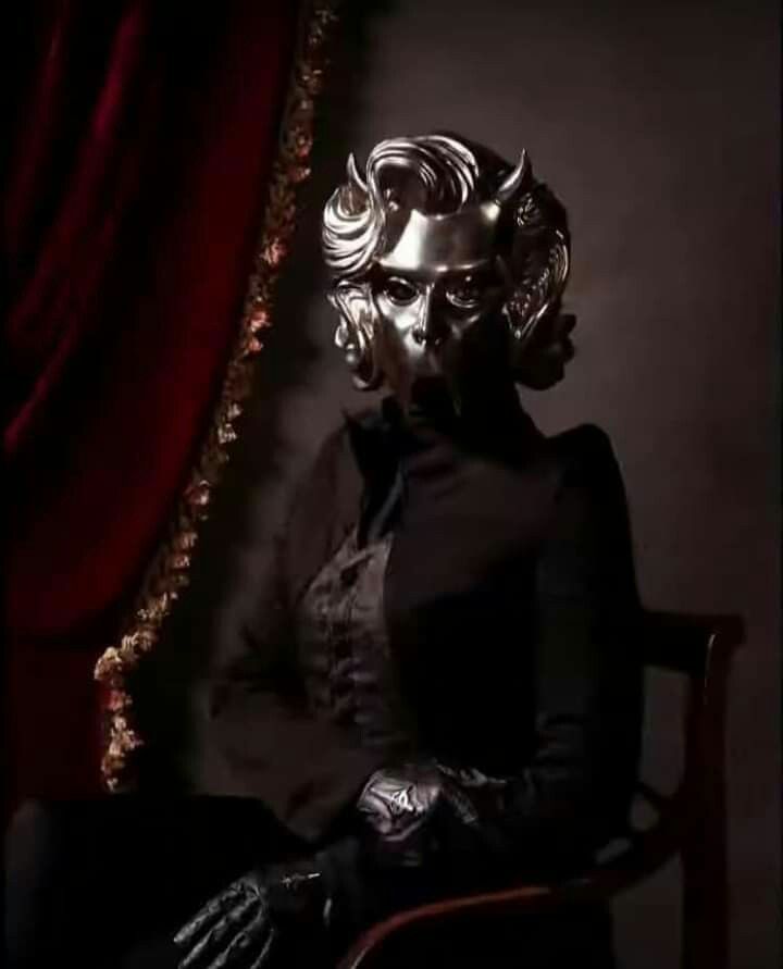 a woman sitting in a chair with her hands on her hips wearing a mask and gloves