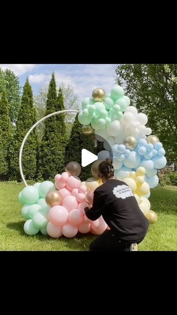 a man kneeling down next to a bunch of balloons on top of a lush green field