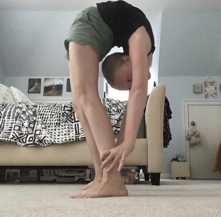 a person doing a handstand on the floor in front of a bed and a chair