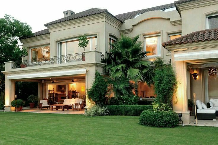 a large house with an outdoor living area and patio in the front yard at dusk