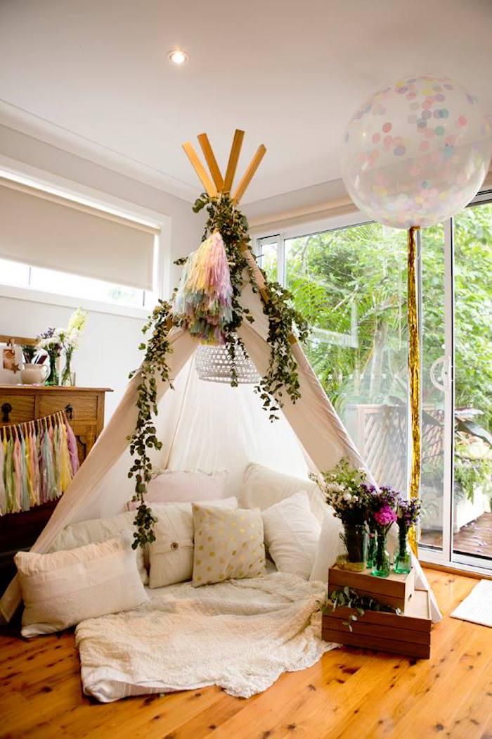 a teepee tent with plants growing out of it and pillows on the floor next to it