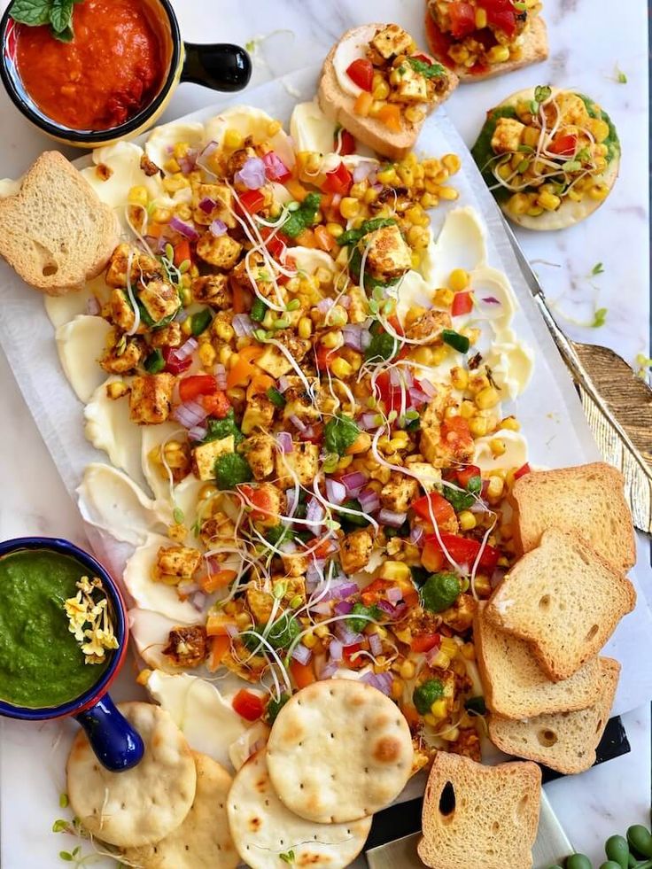 a platter filled with different types of food next to dipping sauces and crackers