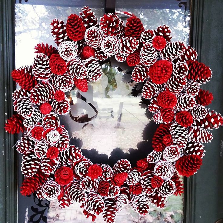 a red and white wreath with pine cones