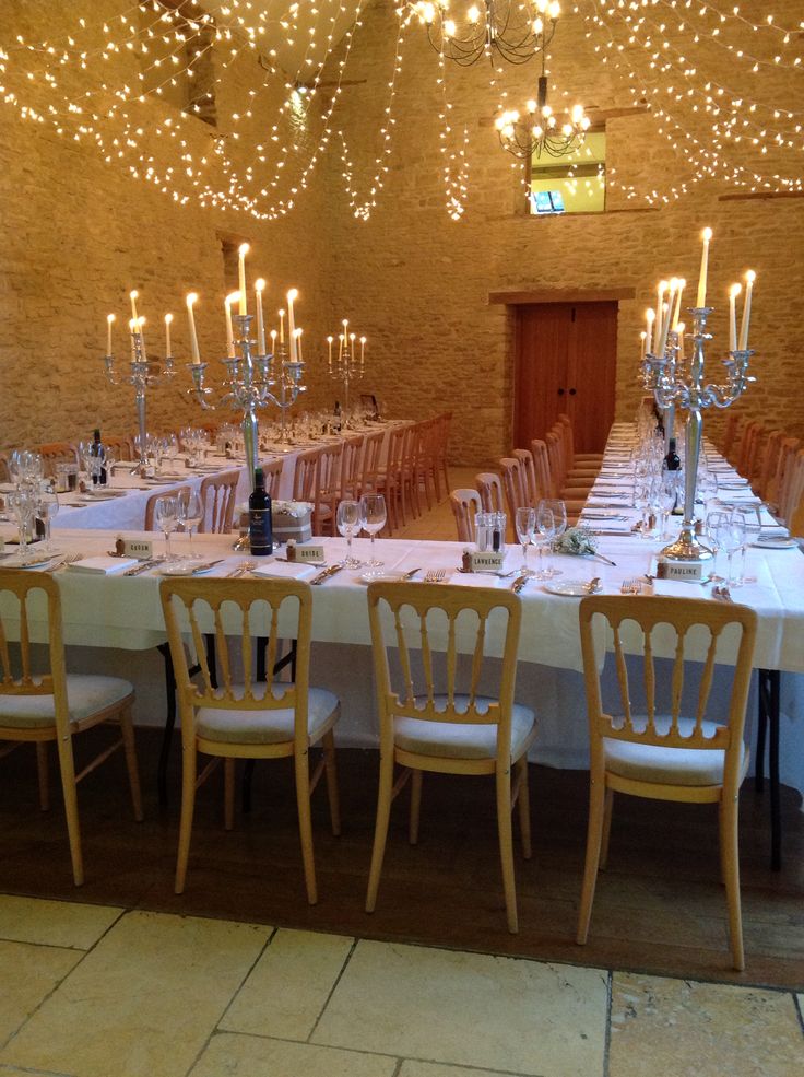 a long table is set up with white linens and lit candles in the middle