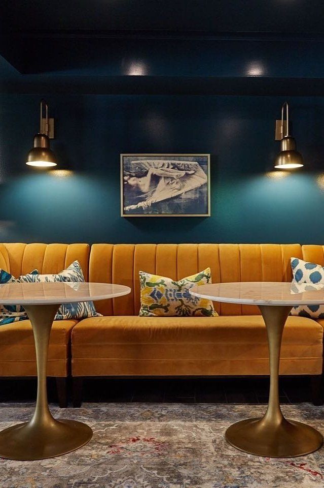 a room with two couches, tables and lamps on the wall above them in front of blue walls