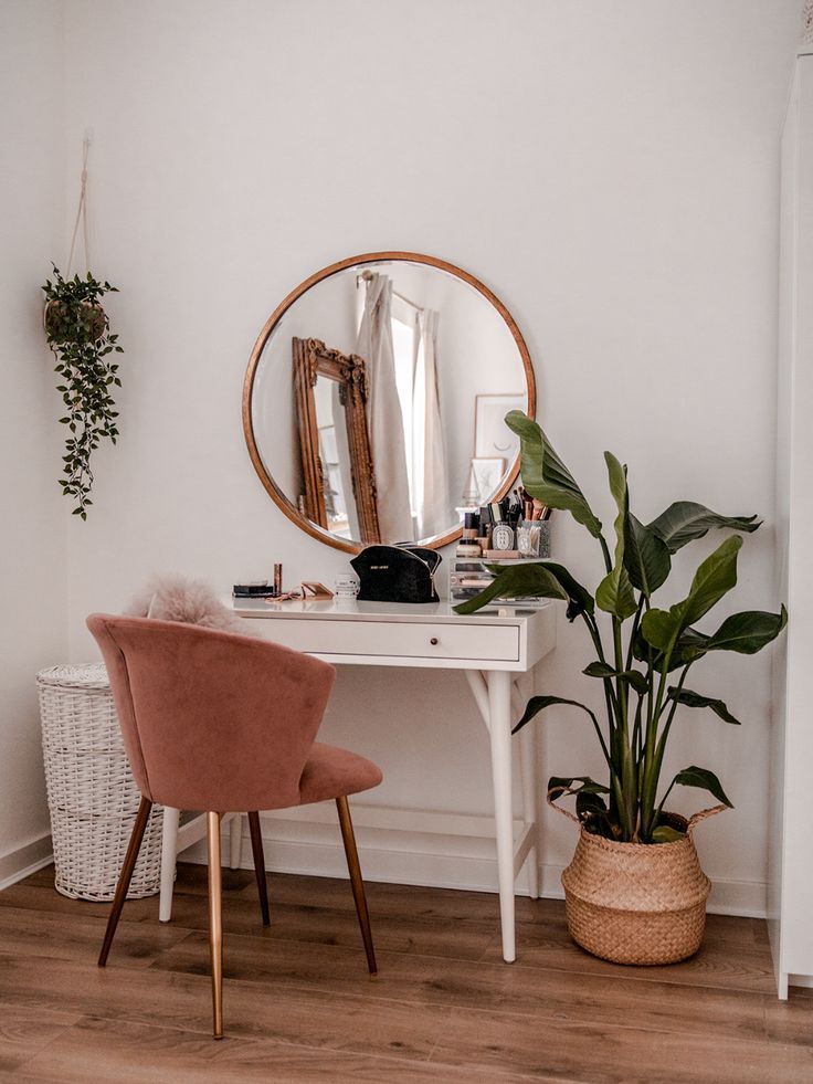 a desk with a mirror, chair and potted plant