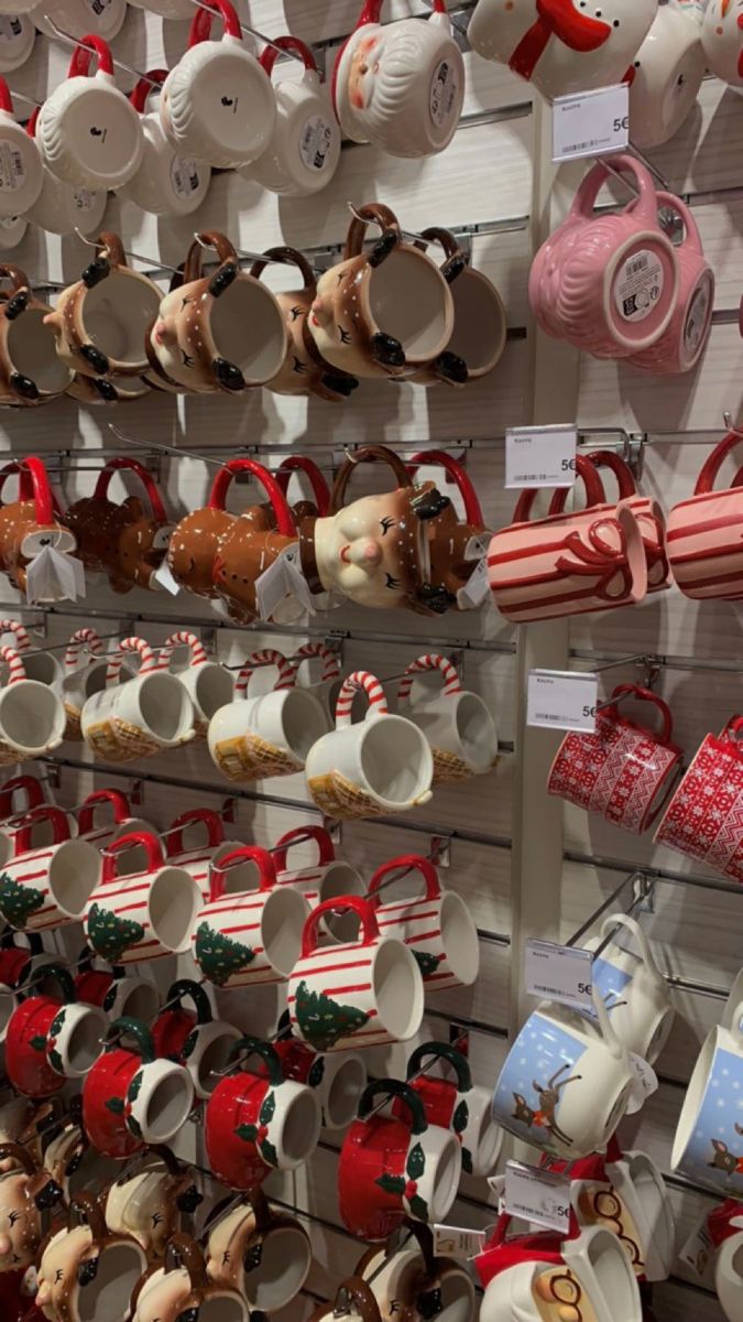 many cups and mugs are hanging on the wall in a store with christmas decorations