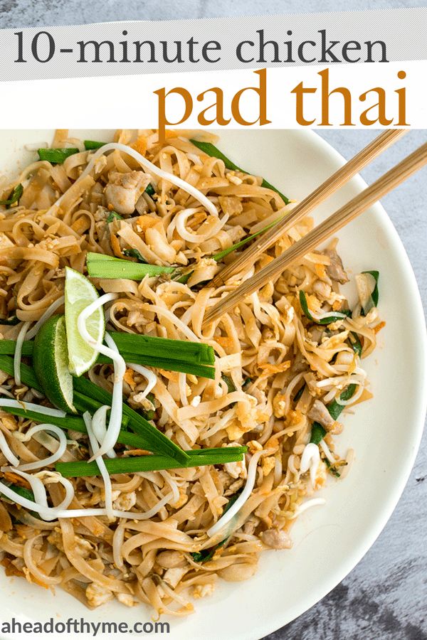 a white plate topped with pad thai noodles and green onions next to chopsticks