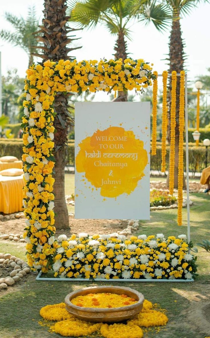 yellow and white flowers decorate the entrance to a wedding ceremony with a sign in the background