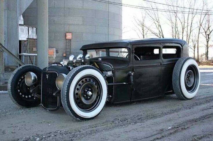 an old black car is parked on the side of the road