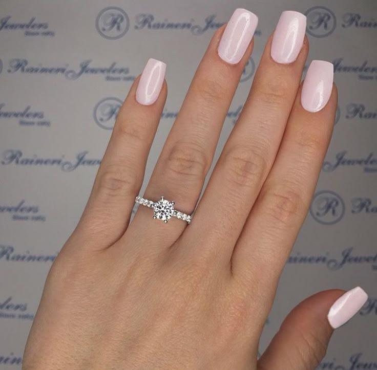 a woman's hand with a pink manicured nail polish and a diamond ring