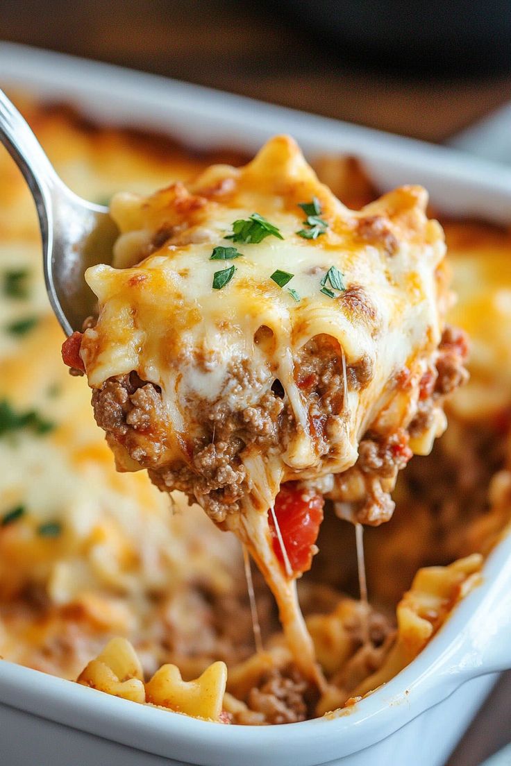 a spoon full of lasagna casserole being lifted from the casserole dish