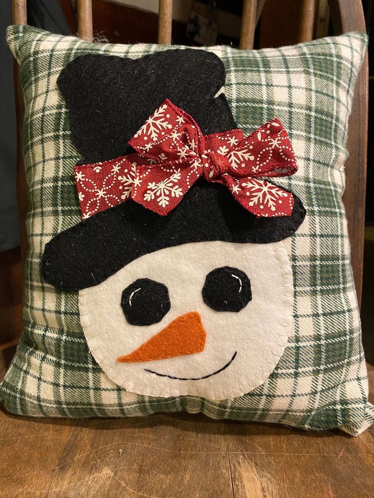 a snowman pillow with a red bow on it's head sitting on a chair