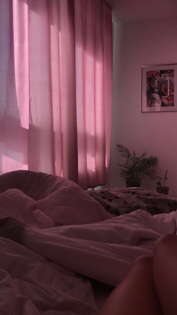 a person laying in bed with pink sheets