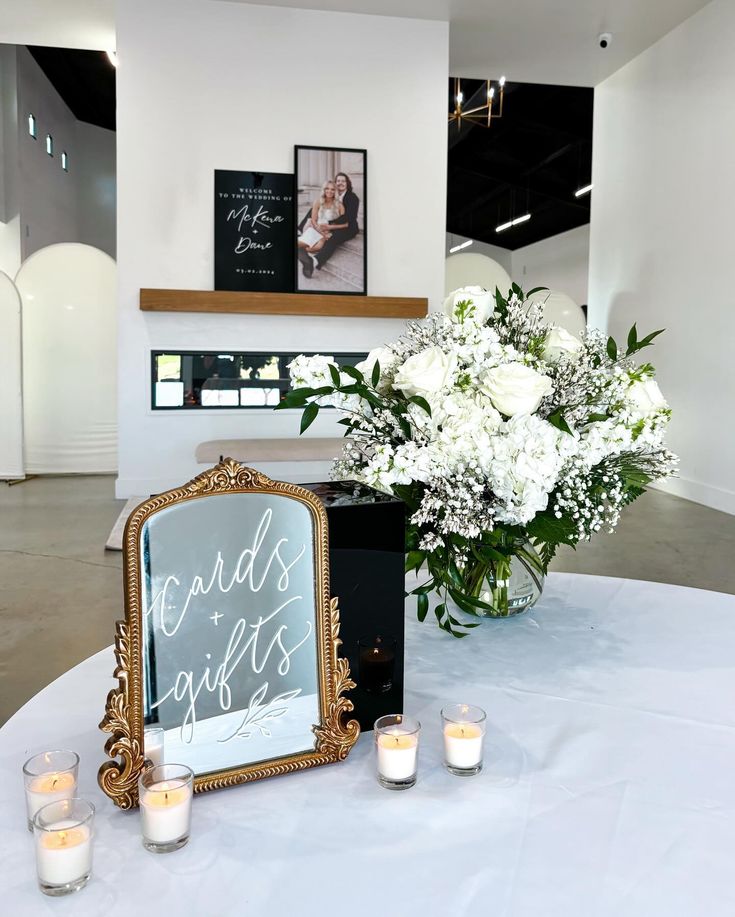 white flowers and candles are sitting on a table with a sign that says grands gifts