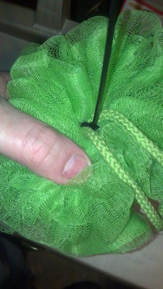 a persons hand with a pair of scissors in the middle of a piece of green cloth