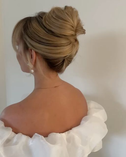 a woman in a white dress with her hair up and looking off to the side