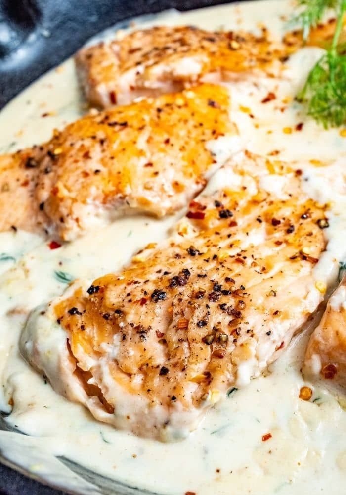 some chicken is covered in white sauce and garnished with parsley