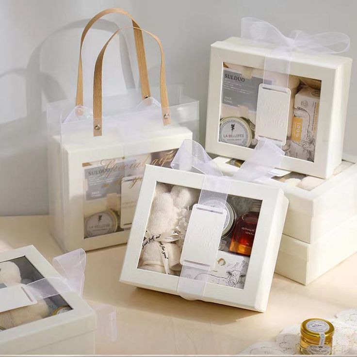 three white boxes with pictures and ribbons on them sitting on a table next to other items