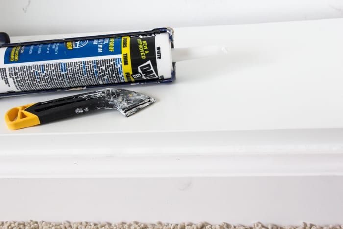 a tube of glue sitting on top of a white shelf next to a yellow handled razor