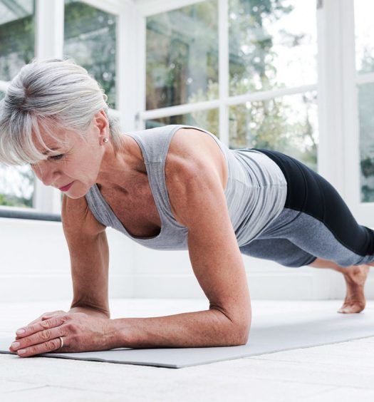 an older woman is doing push ups on the floor