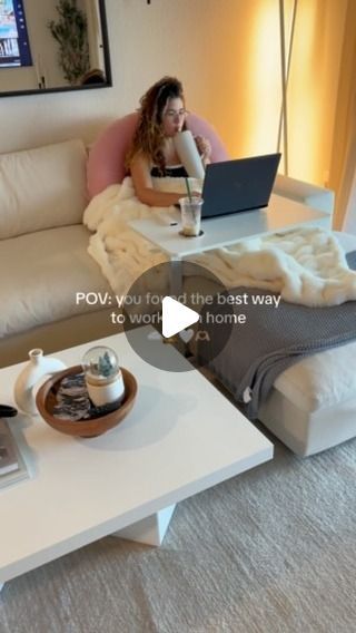 a woman sitting on a couch with a laptop computer in front of her and coffee table next to her