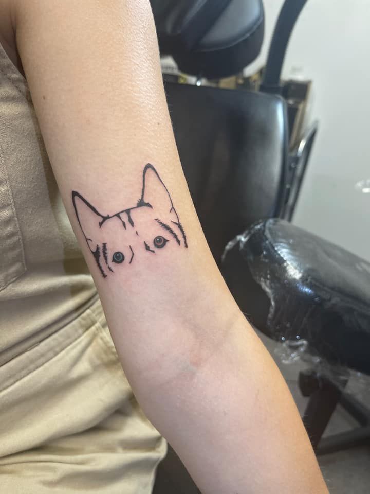 a woman's arm with a small tattoo of a dog on the left side of her arm