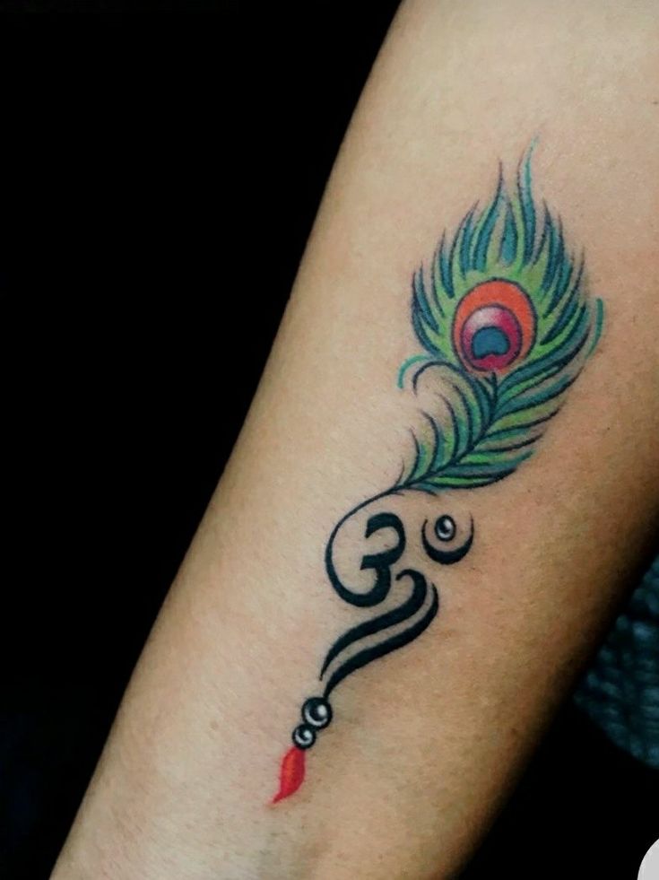 a peacock feather tattoo on the arm with an omen symbol in black and red