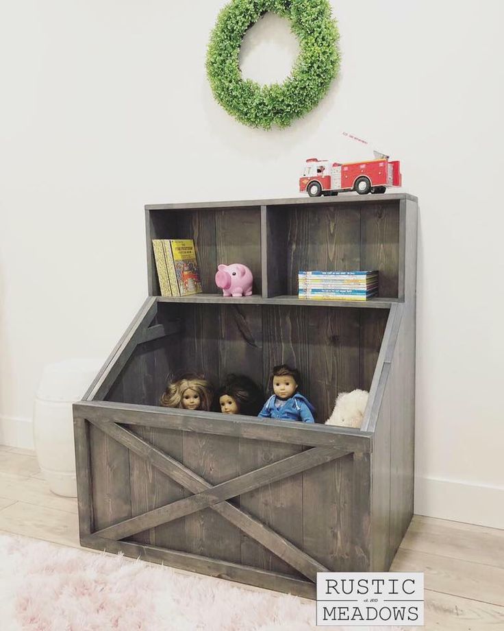 a wooden toy box with stuffed animals in it and a wreath on the wall above