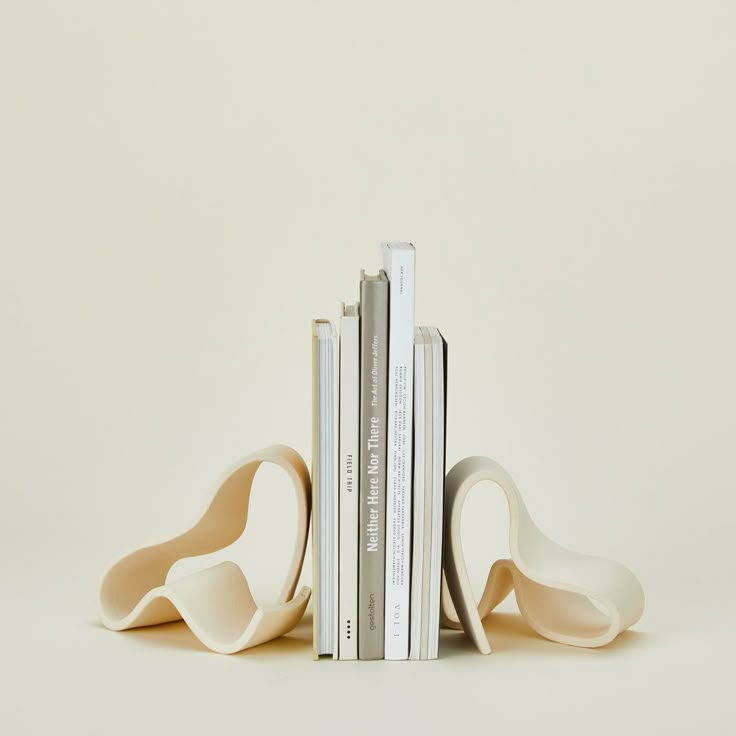 three books stacked on top of each other in front of a white wall with two bookends