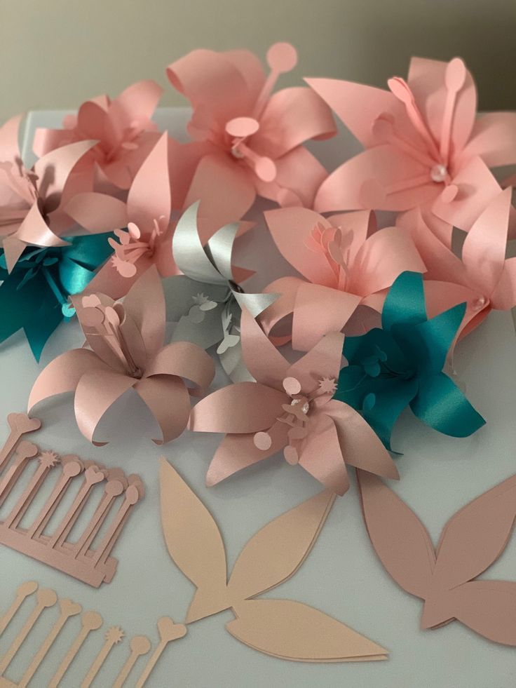 pink and blue paper flowers are on top of a white table with scissors, combs and cutters