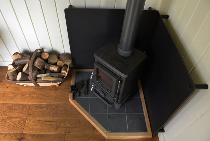 a wood burning stove sitting on top of a wooden floor next to a pile of logs